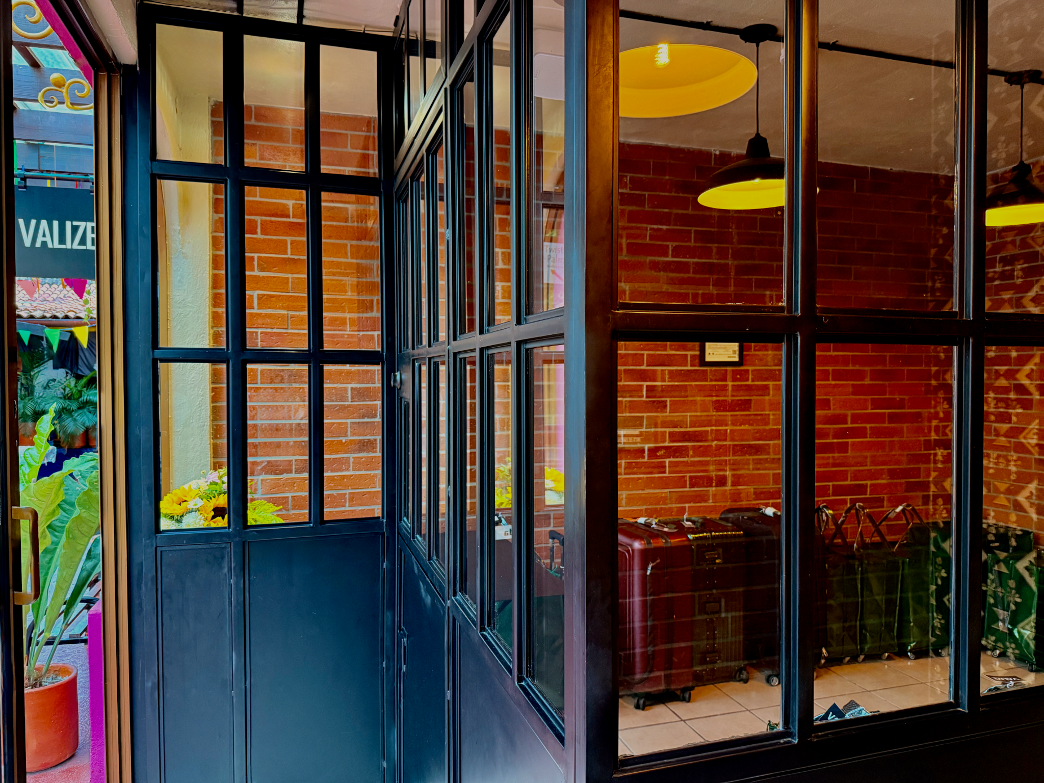 Inside VALIZE Cloakroom, with black-framed glass partitions, warm lighting, and checked suitcases visible in the holding area